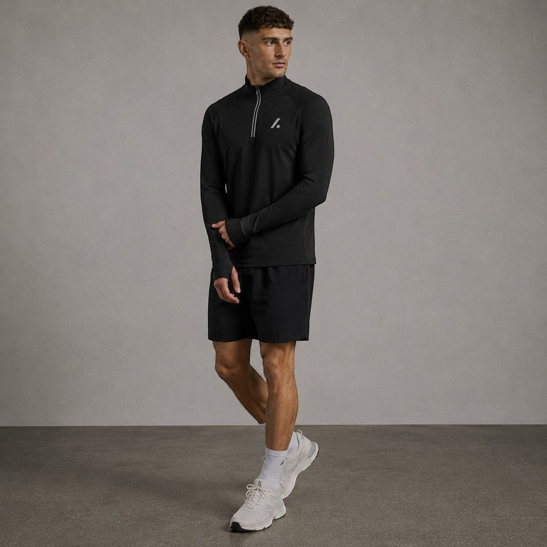 TwentyTenCollective black long sleeve performance quarter zip athletic top with thumbholes and reflective detailing.