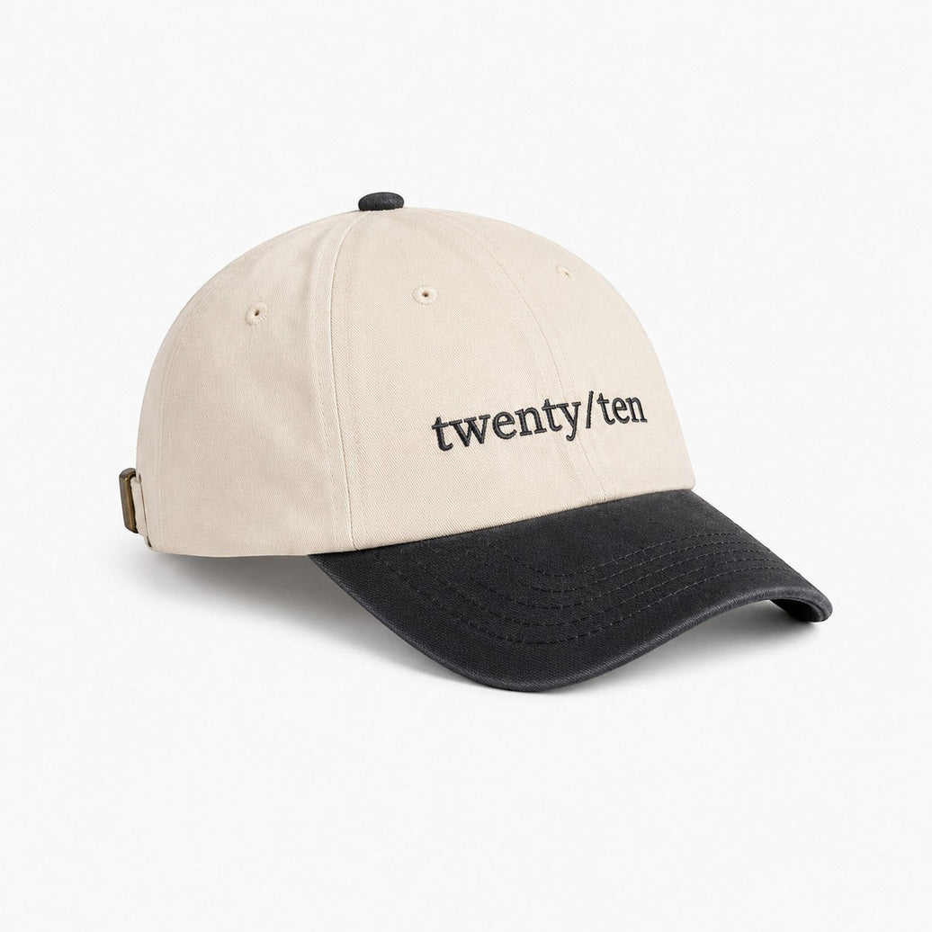 TwentyTenCollective cream cotton baseball cap with charcoal brim and embroidered logo. Adjustable strap.