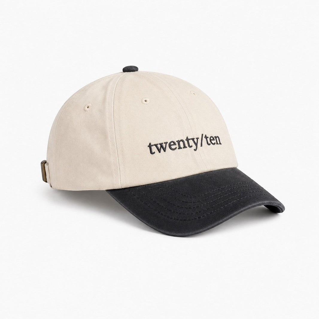 TwentyTenCollective cream cotton baseball cap with charcoal brim and embroidered logo. Adjustable strap.