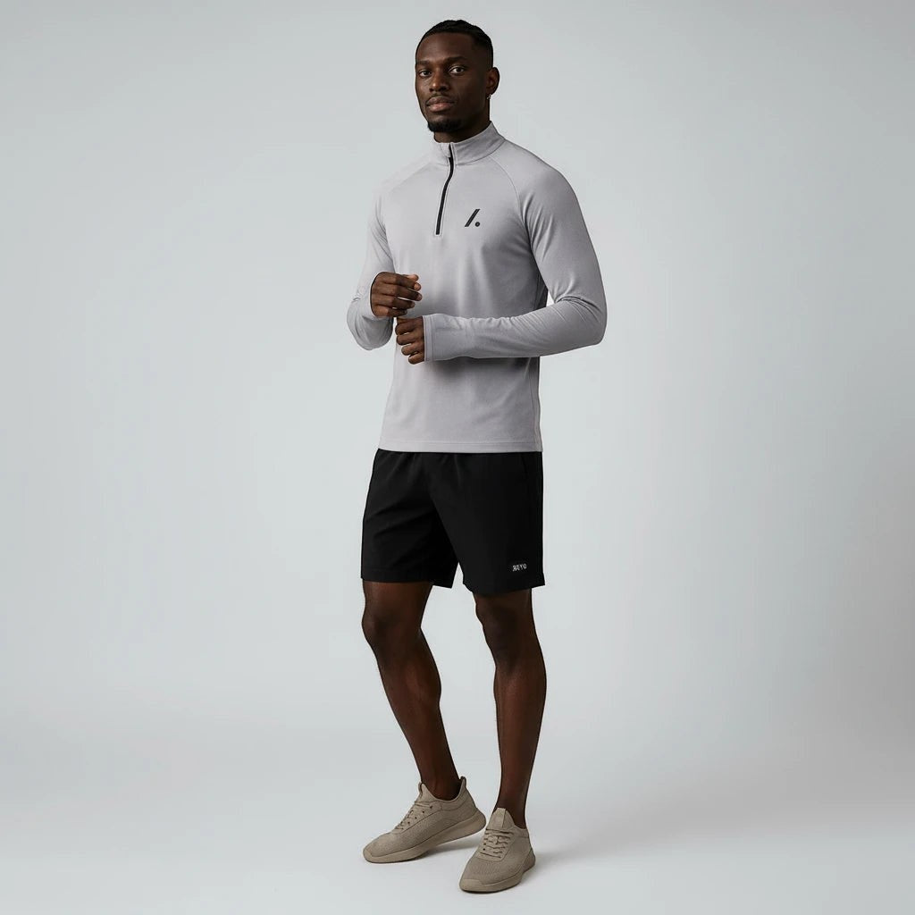 TwentyTenCollective men's light grey quarter zip long sleeve athletic shirt with thumbholes and black shorts.
