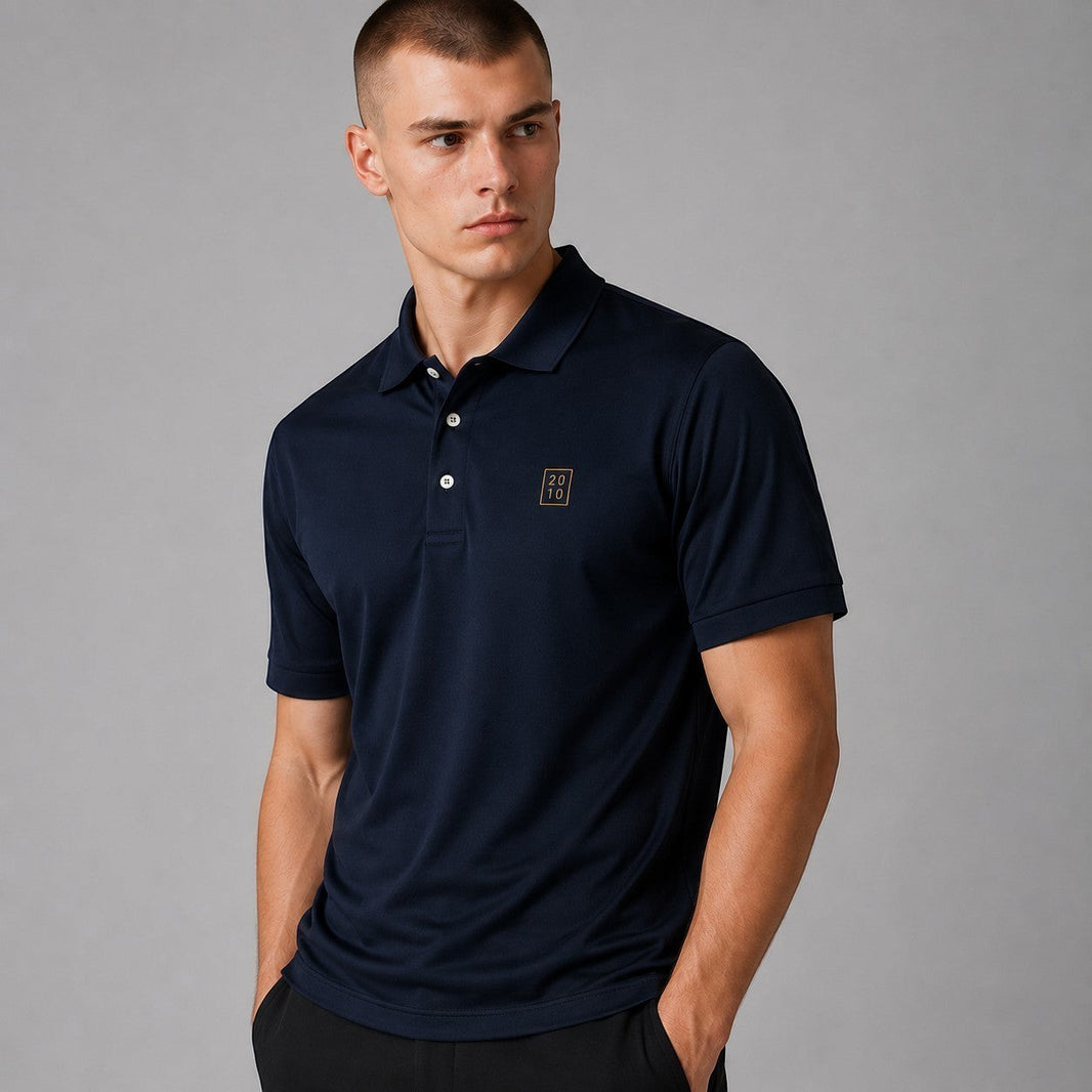 TwentyTenCollective classic navy blue short sleeve polo shirt with embroidered emblem on chest. Model is wearing a size M.