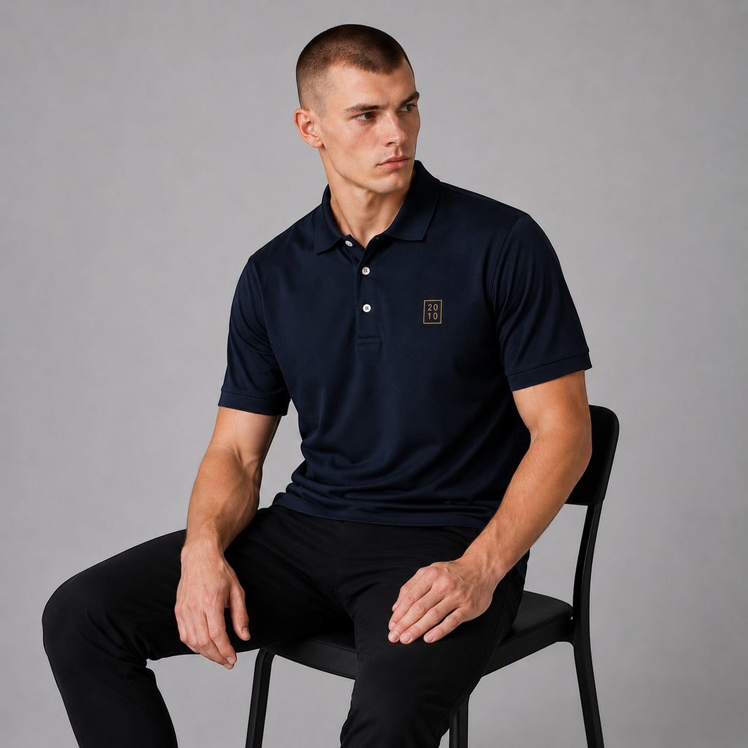 TwentyTenCollective navy blue short sleeve polo shirt with embroidered emblem on chest, classic collar, and button placket.