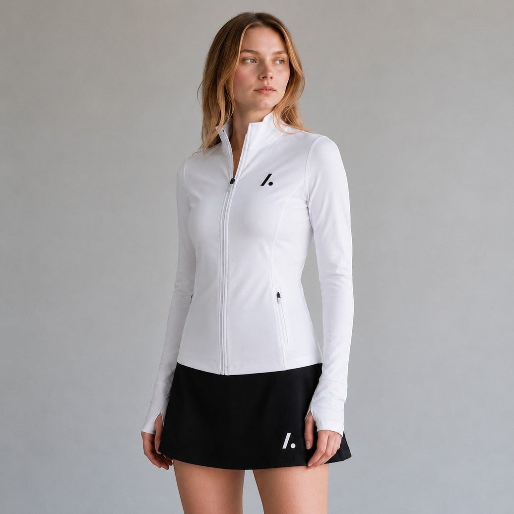 TwentyTenCollective white athletic full-zip jacket with mock neck, thumbholes, and zippered pockets. Model is wearing a black skirt.