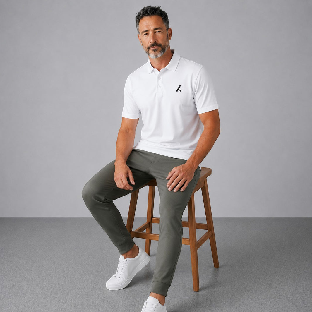 TwentyTenCollective white performance polo shirt and olive green jogger pants set on a seated man.