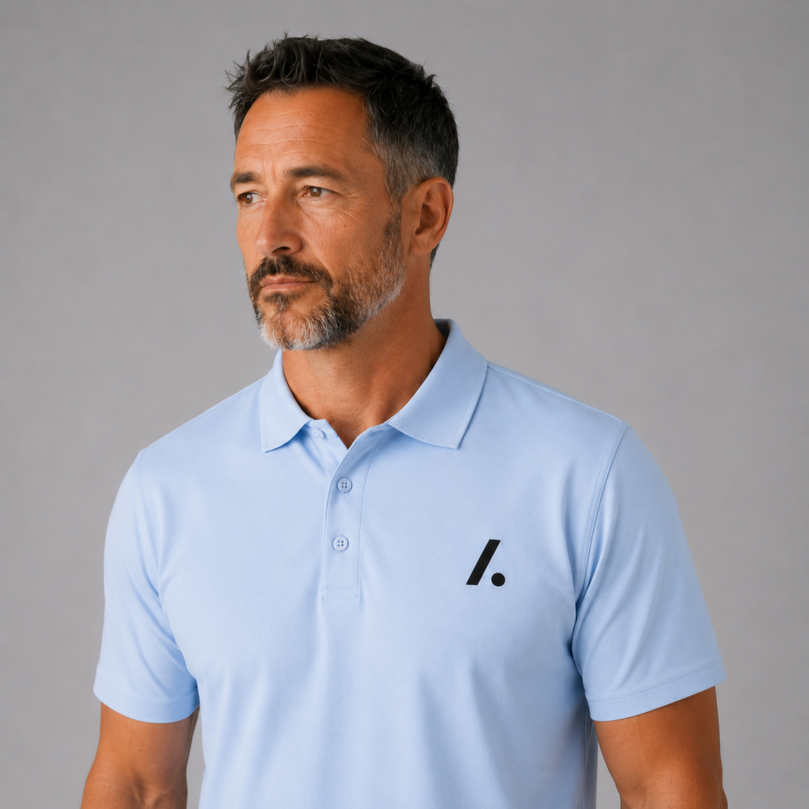Man wearing a light blue polo shirt with a logo on a gray background