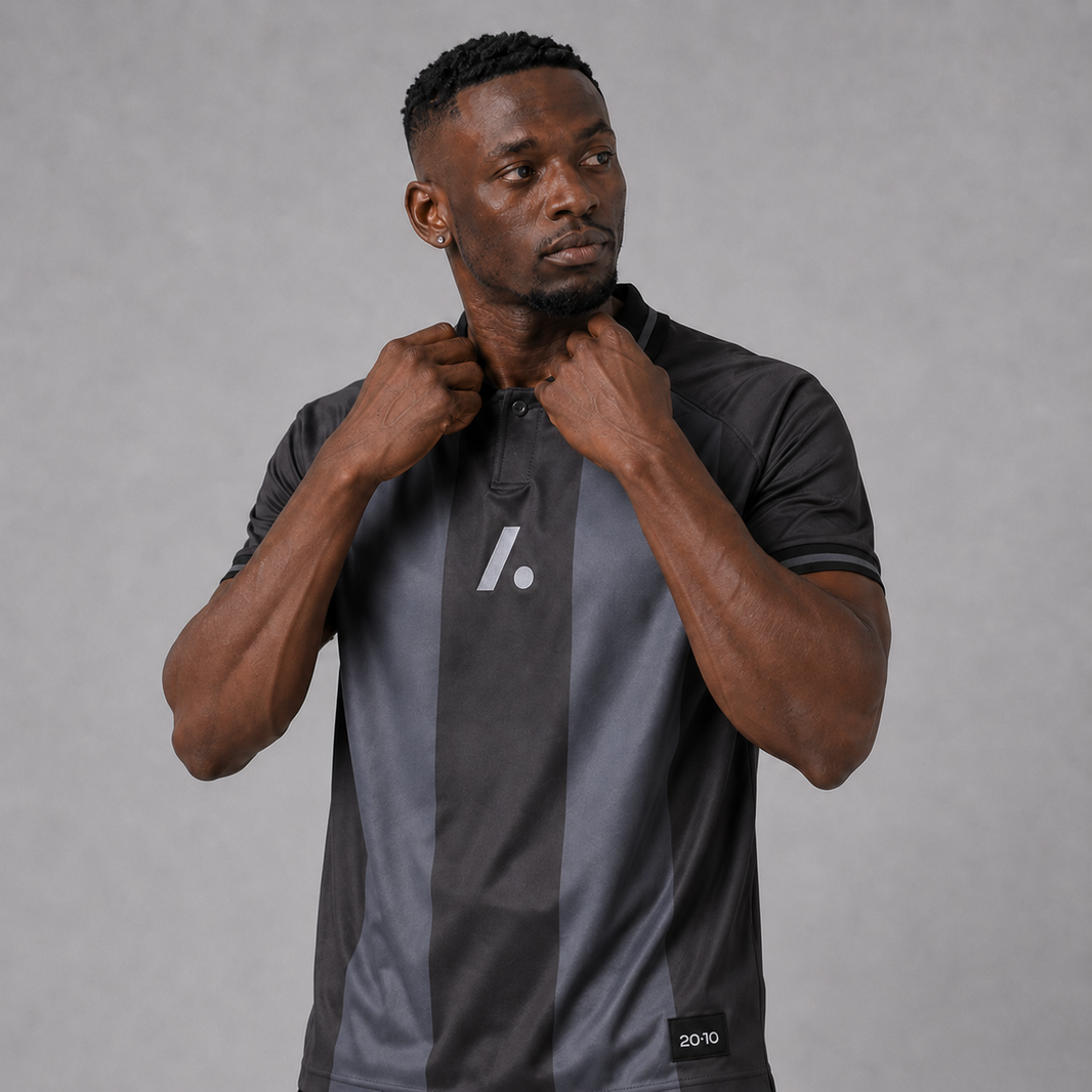 Man wearing a black and gray sports jacket with a logo on a gray background