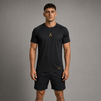 Man wearing a black t-shirt and shorts with a logo on a gray background