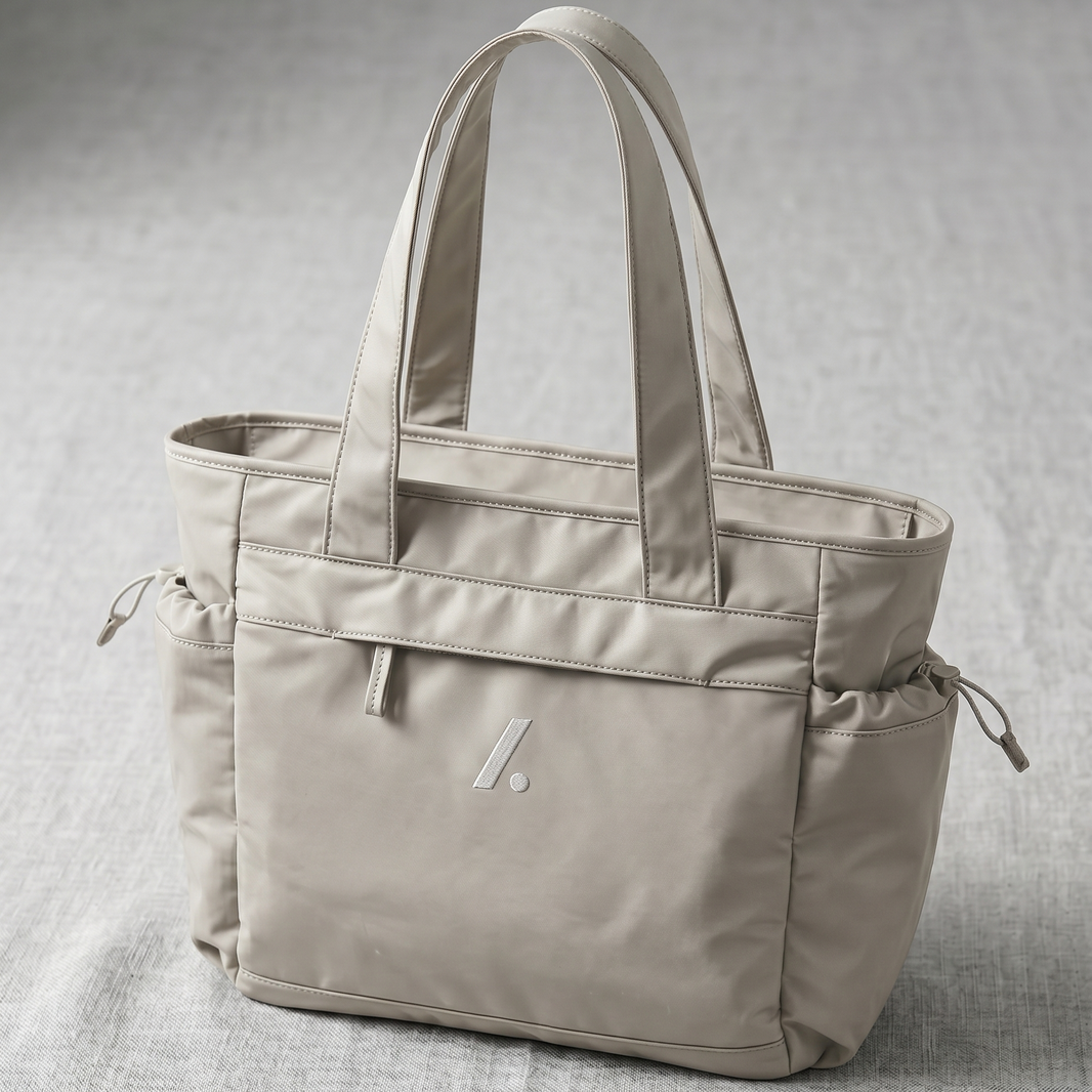 Beige tote bag with a visible brand logo on a gray background
