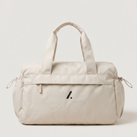 Beige duffel bag with a logo on a light gray background