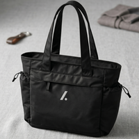 Black tote bag with a logo on a gray surface