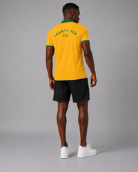 Person wearing a yellow polo shirt with 'Twenty Ten Co.' branding on the back, standing against a gray background.
