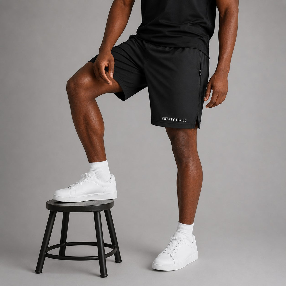 Twenty Ten Co. black athletic performance shorts with zippered pockets and elastic waistband, worn by a man.