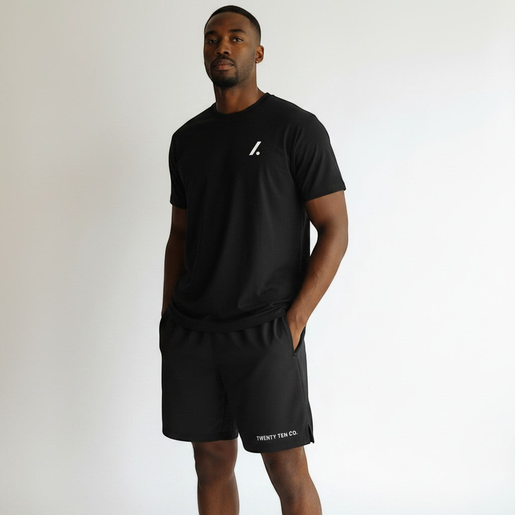 Twenty Ten Co. black athletic performance shorts with zippered pockets and elastic waistband. Model is wearing a black t-shirt.
