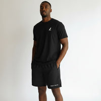 Twenty Ten Co. black athletic performance shorts with zippered pockets and elastic waistband. Model is wearing a black t-shirt.