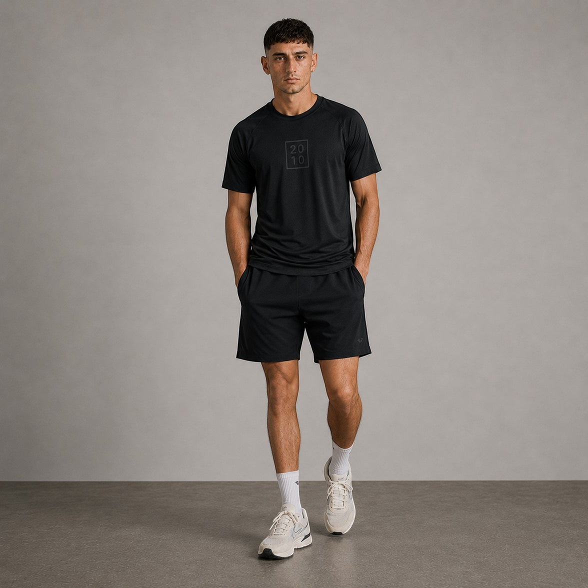 TwentyTenCollective black athletic t-shirt with raglan sleeves and tonal chest logo, worn by a man.