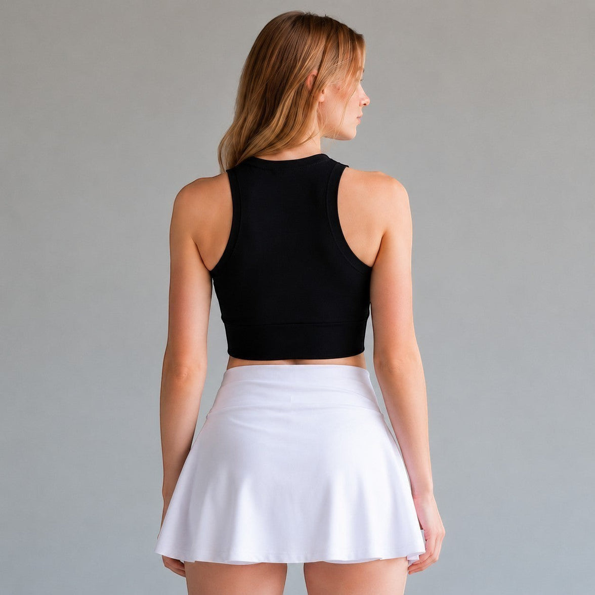 TwentyTenCollective black athletic tank top and white skort on a woman from behind.