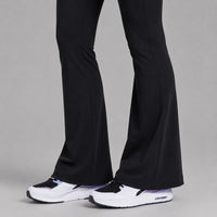 TwentyTenCollective black recycled polyester flared leggings with hidden pocket and white sneakers.