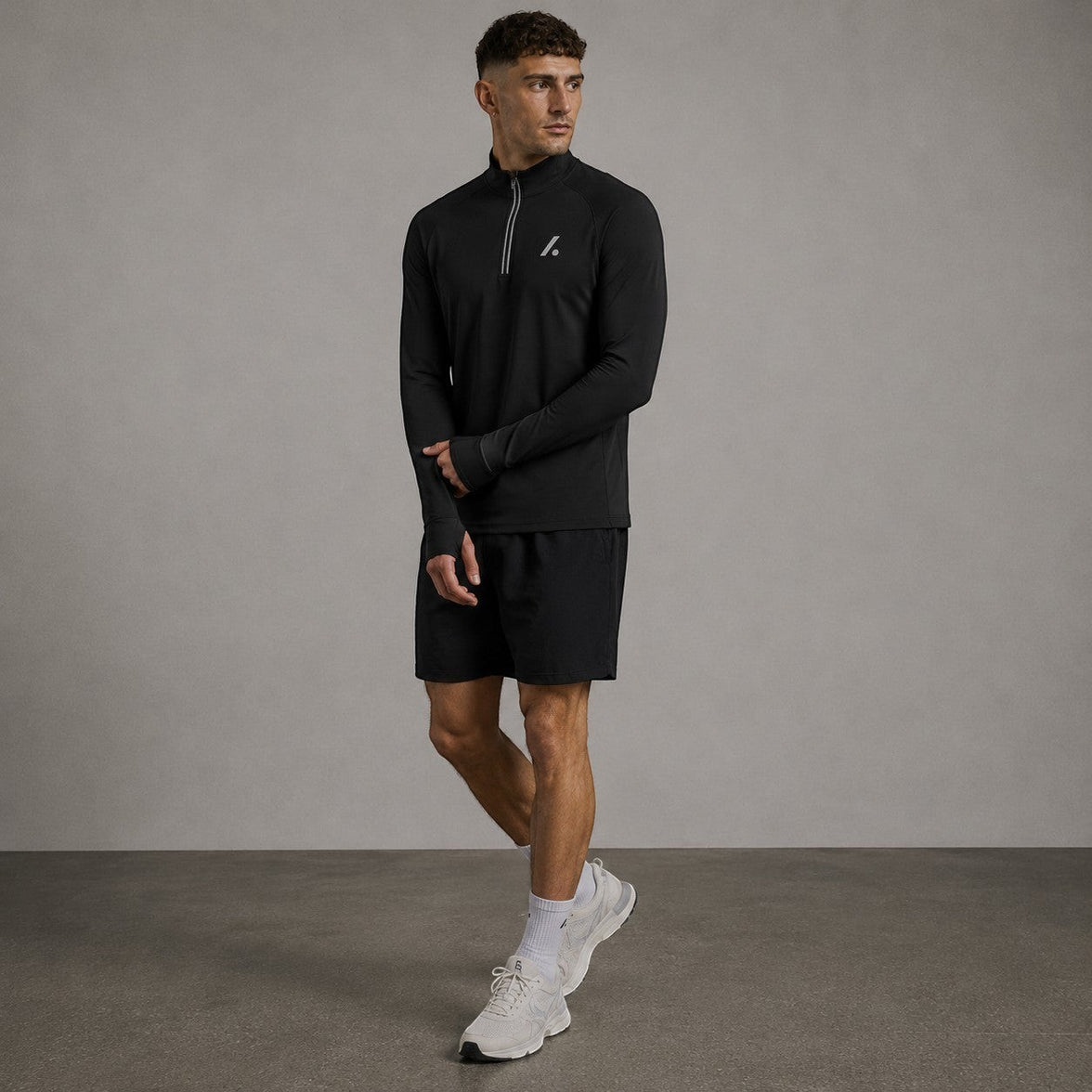 TwentyTenCollective black long sleeve performance quarter zip athletic top with thumbholes and reflective detailing.