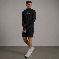 TwentyTenCollective black long sleeve performance quarter zip athletic top with thumbholes and reflective detailing.