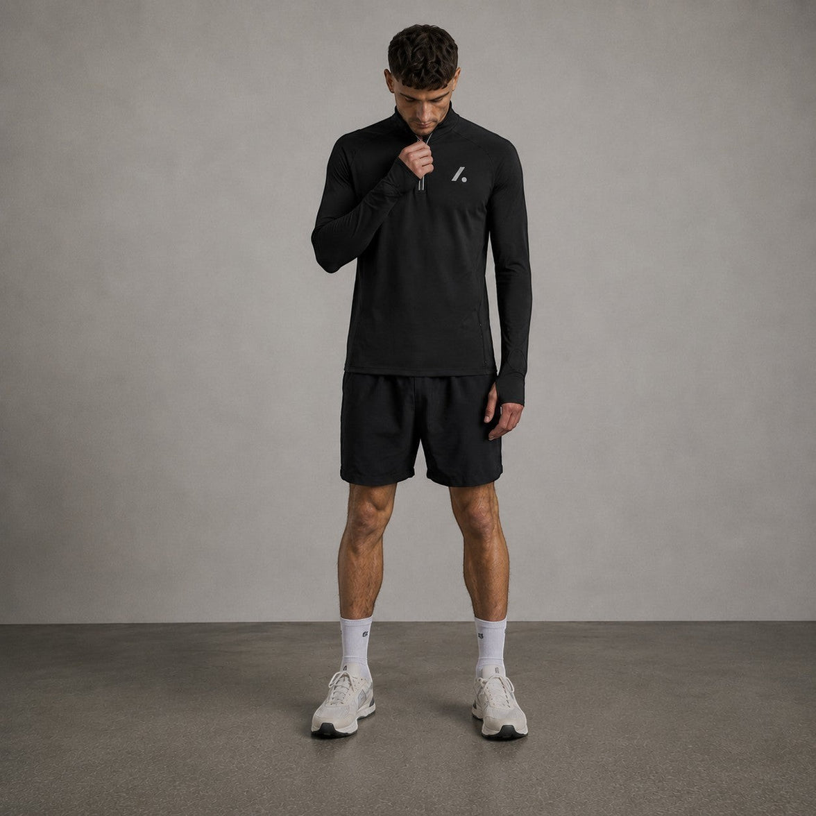 TwentyTenCollective black performance quarter zip long sleeve athletic top with thumbholes and reflective detailing.