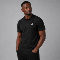 TwentyTenCollective black short sleeve polo shirt with white logo on chest and ribbed collar.