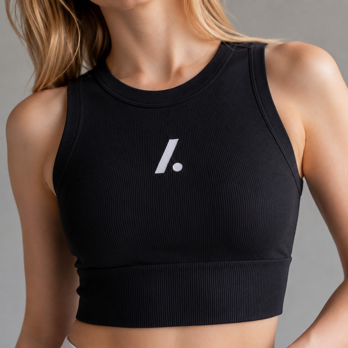 TwentyTenCollective black ribbed athletic tank top with white logo detail. Sleeveless, high neckline, cropped length.