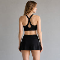 TwentyTenCollective black athletic sports bra with criss-cross straps and matching skort with integrated shorts.