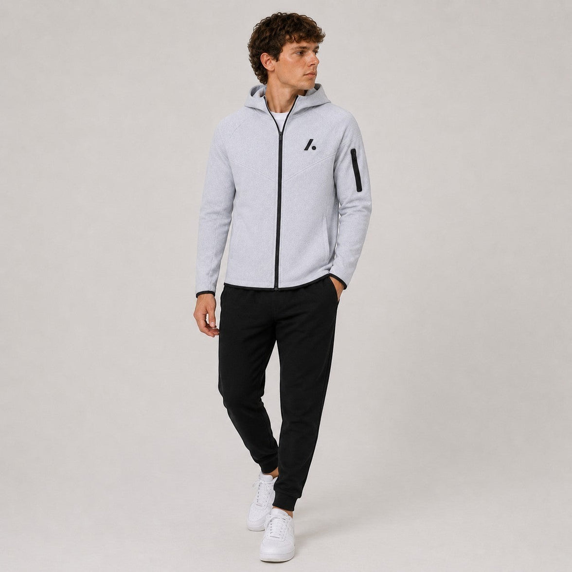 TwentyTenCollective light grey tech fleece zip-up hoodie with black logo and zippered sleeve pocket.