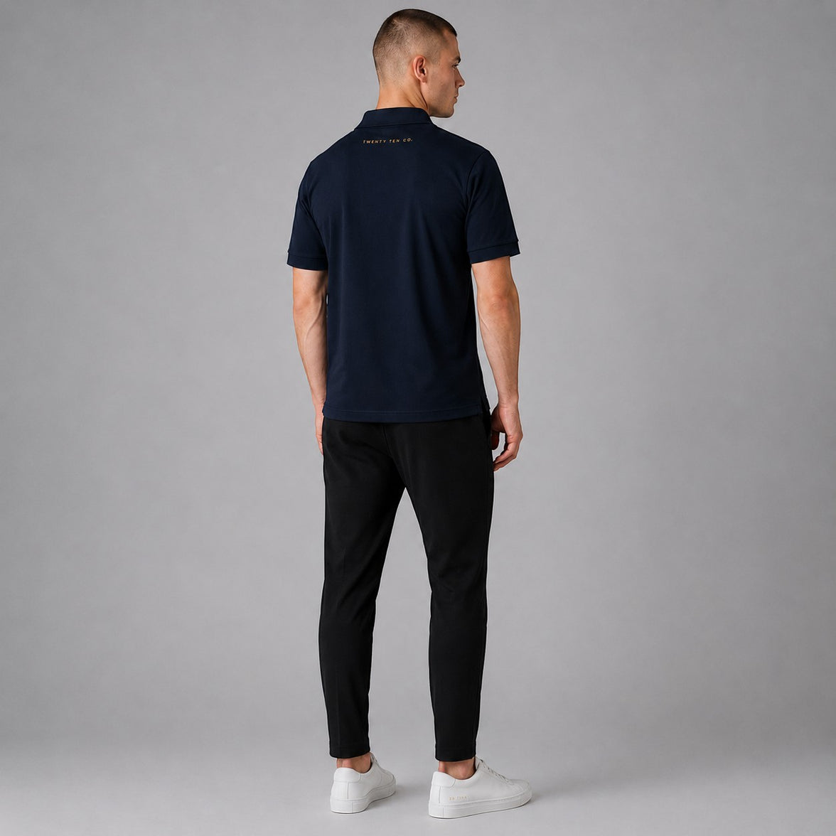 TwentyTenCollective classic navy blue short sleeve polo shirt with embroidered logo on back, worn by a man.