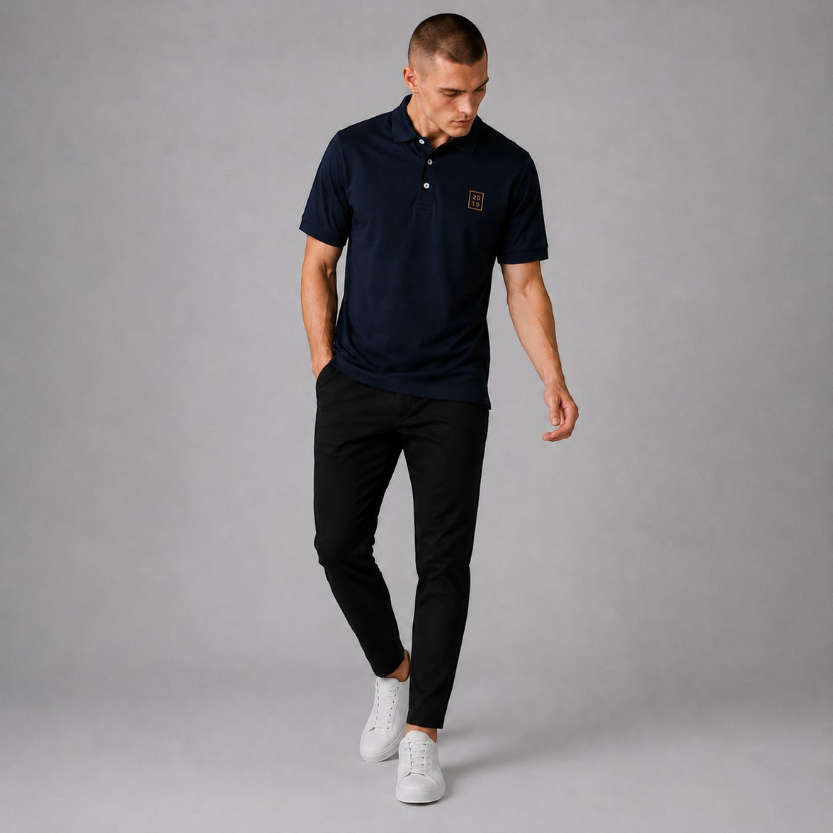 TwentyTenCollective navy blue short sleeve polo shirt with embroidered emblem on chest, classic collar, and white buttons.