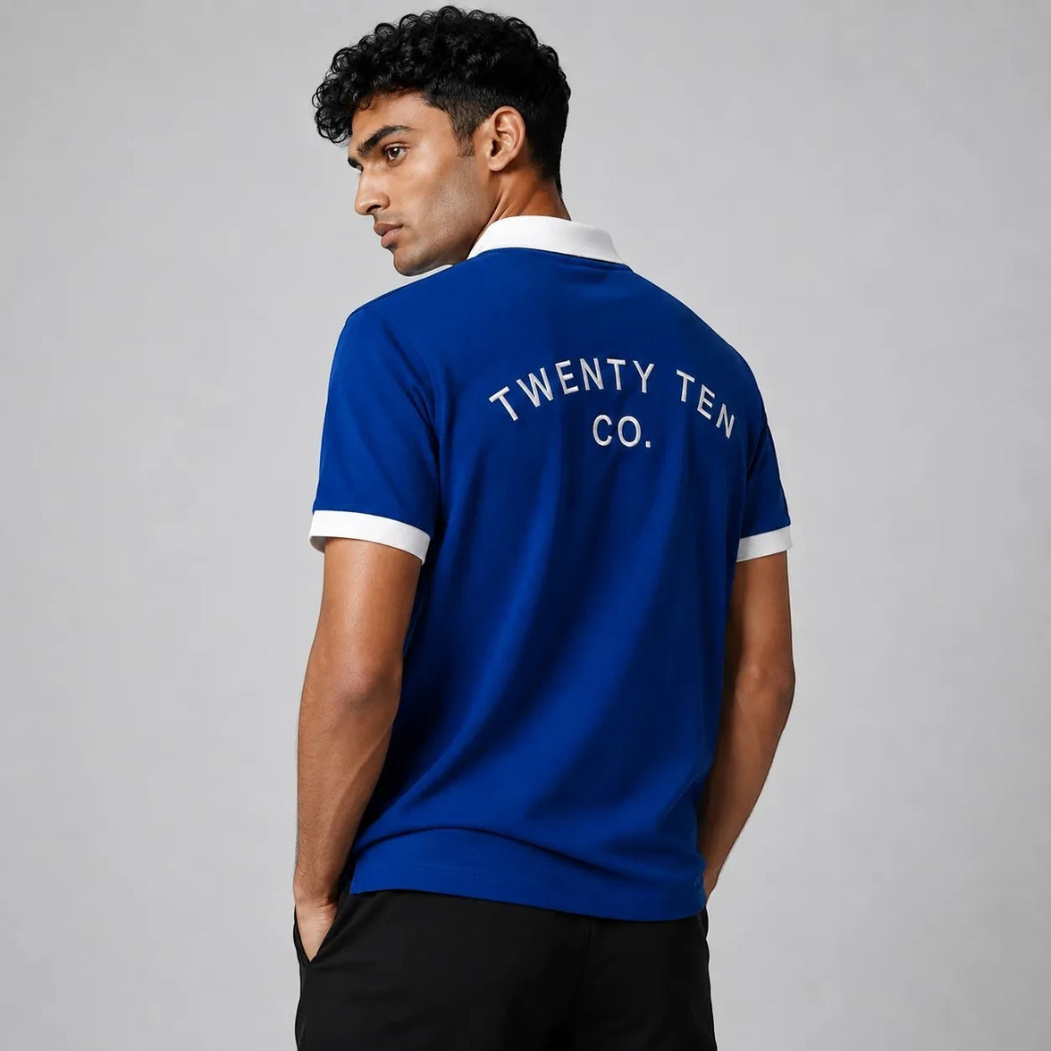 TwentyTenCollective royal blue athletic shirt with white trim on collar and cuffs, and white text print on back.