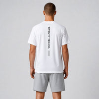 TwentyTenCollective white athletic performance t-shirt with vertical logo detail and grey shorts. Model from behind.