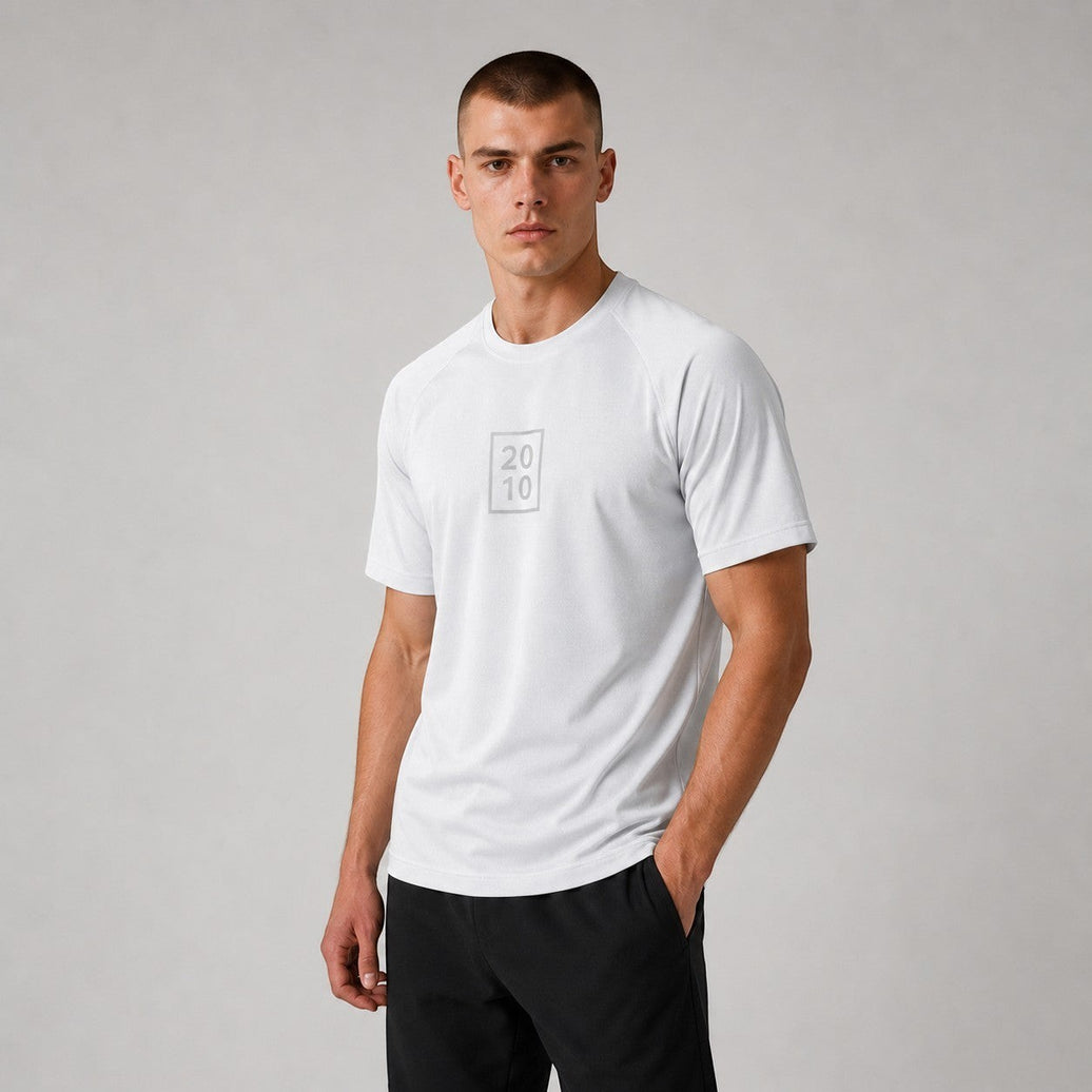 TwentyTenCollective white performance athletic t-shirt with crew neck and subtle chest graphic. Model wearing black athletic shorts.
