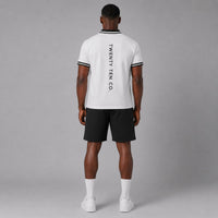 TwentyTenCollective men's white short sleeve polo shirt with black striped collar and cuffs, and vertical logo on back.