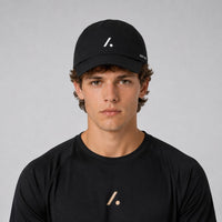 TwentyTenCo black performance baseball cap with white logo and perforated sides, worn by a man.