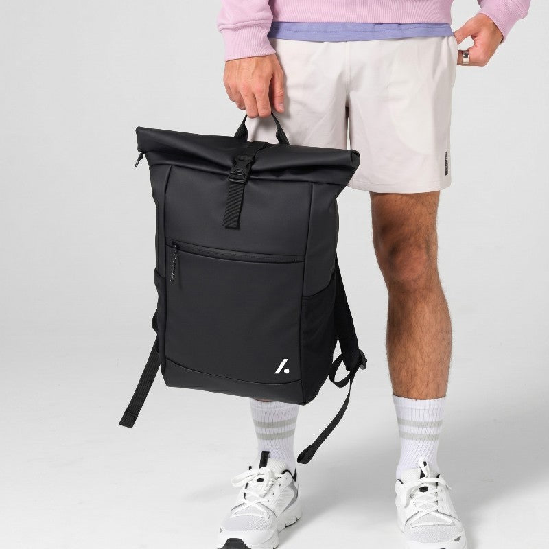 TwentyTenCollective black water-resistant roll-top backpack with buckle closure, external zip pocket, and side mesh pockets.
