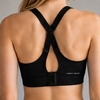 TwentyTenCollective black sports bra with criss-cross adjustable straps and hook-and-eye closure. Features subtle logo.