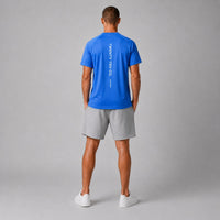 TwentyTenCo. blue athletic t-shirt with vertical white logo graphic on back, worn by a man.