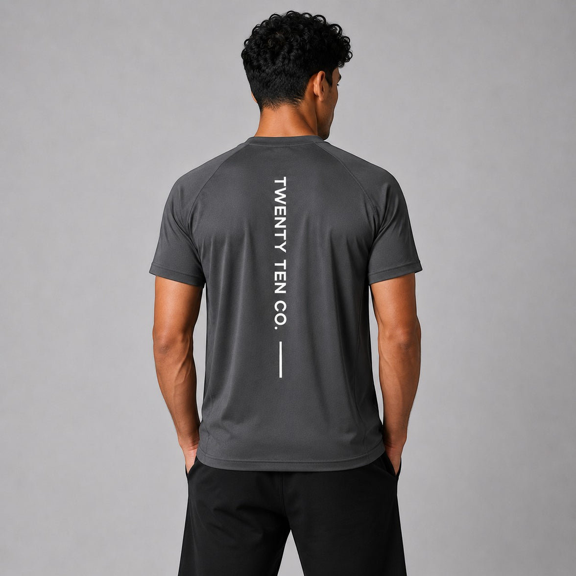 TwentyTenCollective dark grey athletic t-shirt with vertical white TWENTY TEN CO. graphic on back. Model is wearing black shorts.