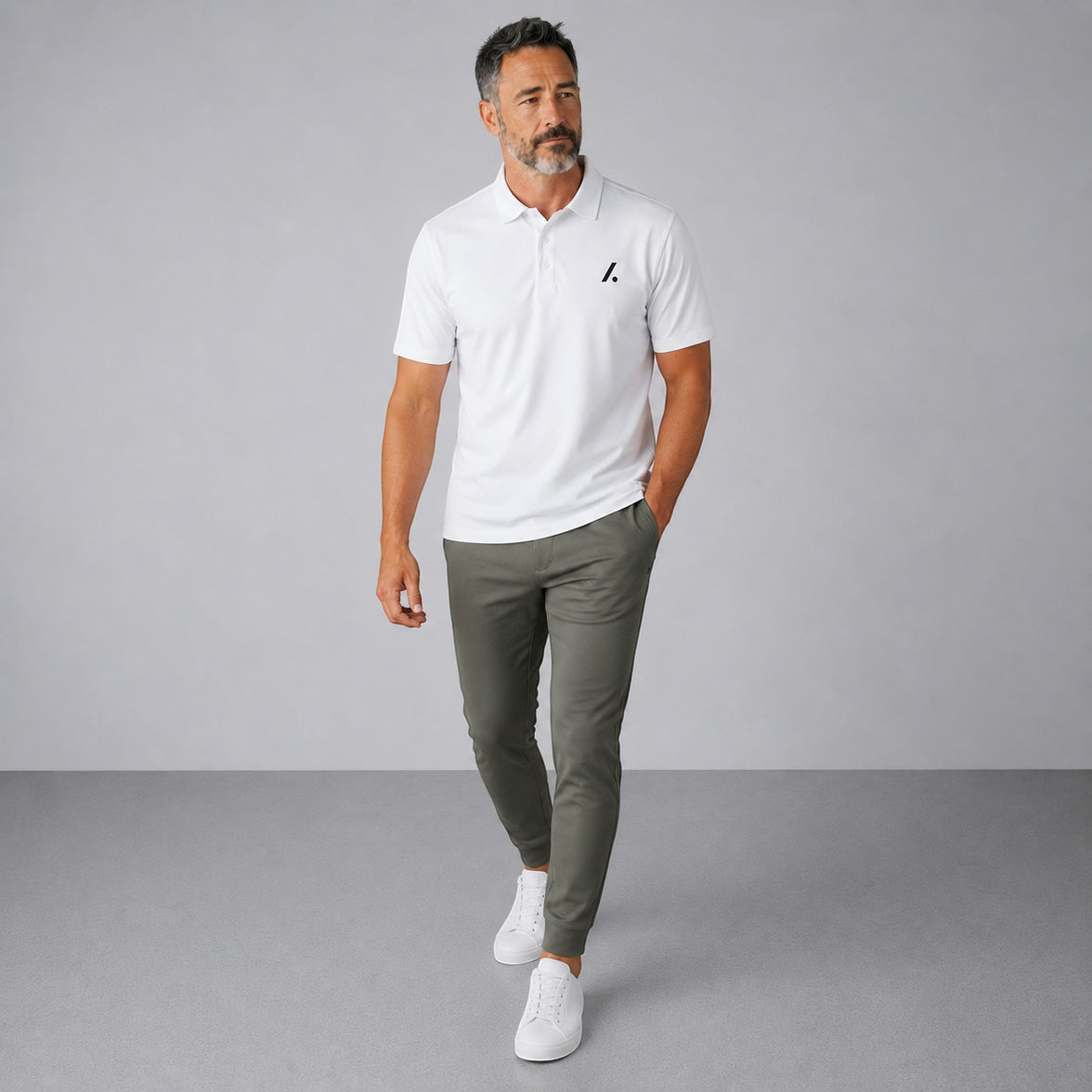 TwentyTenCollective Men's white performance polo shirt and olive green jogger pants set. Model is wearing white sneakers.