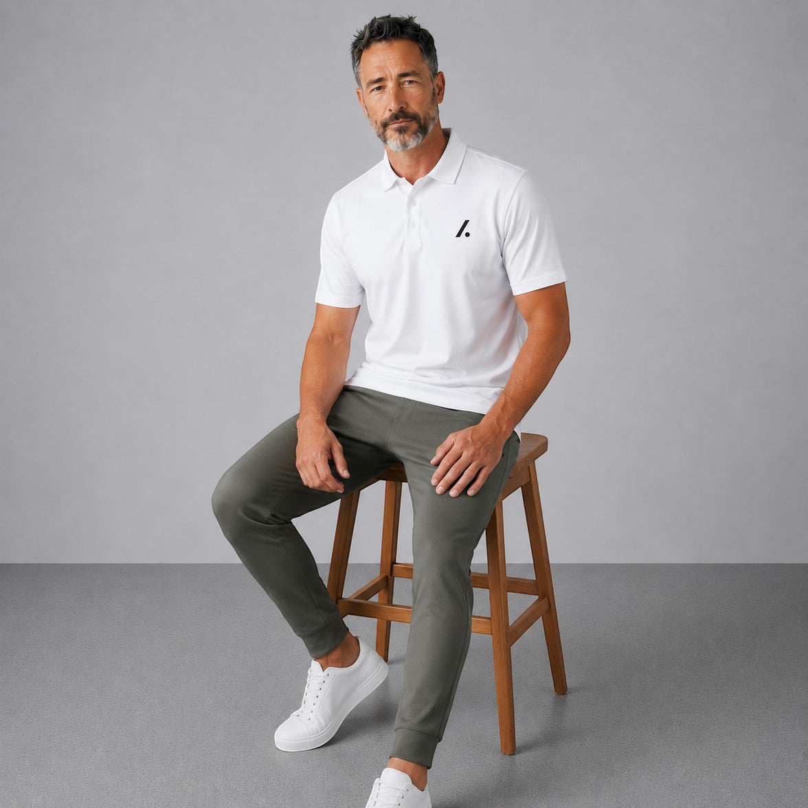 TwentyTenCollective white performance polo shirt and olive green jogger pants set on a seated man.