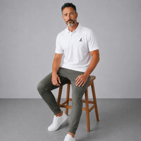 TwentyTenCollective white performance polo shirt and olive green jogger pants set on a seated man.
